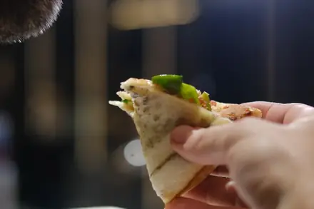 Convidado comendo uma fatia de pizza dobrada durante a festa