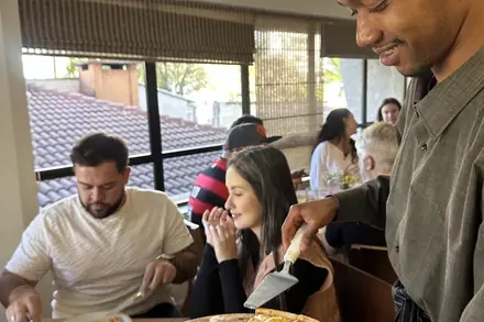 Garçom servindo pizza na mesa dos convidados