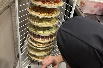 Carrinho com as pizzas montadas, prontas para o forno