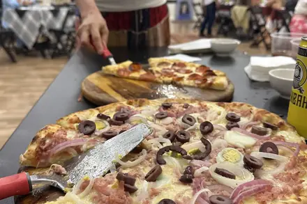 Pizza portuguesa na tábua, com a festa ao fundo