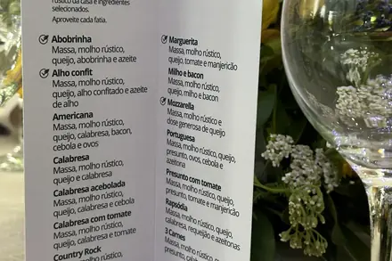 Cardápio impresso com o nome dos noivos e os sabores da noite, na mesa do casamento
