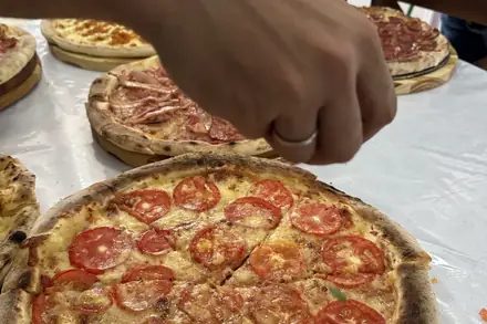 Pizza marguerita sendo finalizada para servir, na bancada do casamento