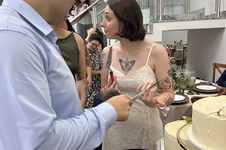 Os noivos junto à mesa do bolo, durante a festa de casamento