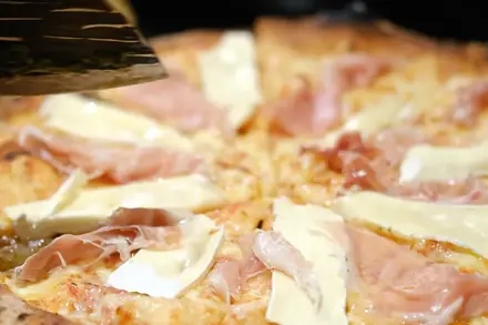 Pizza de presunto cru com queijo brie servida na tábua durante um evento da BeatOven
