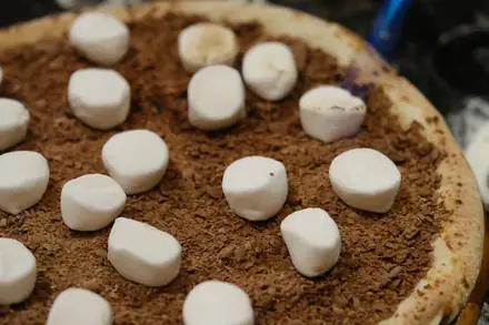 Pizza doce de chocolate sendo finalizada com maçarico na bancada montada no evento