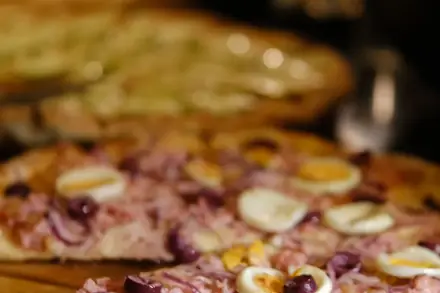 Pizza portuguesa com presunto, ovo, cebola roxa e azeitona, servida na tábua durante um evento da BeatOven