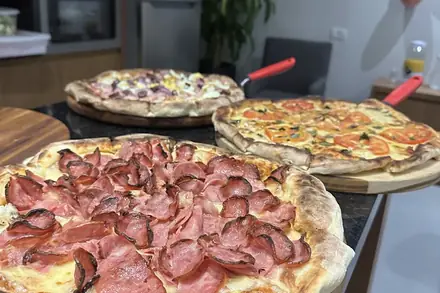 Pizzas do rodízio nas tábuas, sobre a bancada da cozinha de uma casa, durante uma festa
