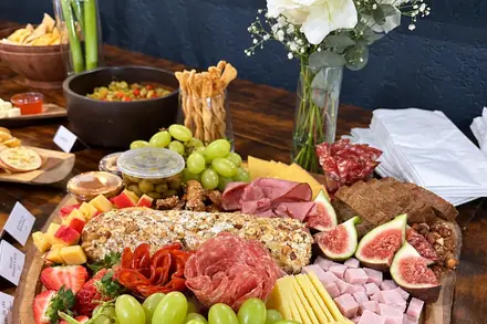 Mesa de frios com cheeselog, figos, uvas e queijos