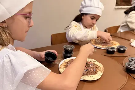 Criança de chapéu de cozinheiro decorando a pizza doce
