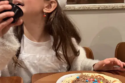 Criança provando a pizza que decorou no Mini Chef