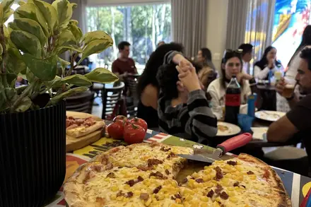 Salão da festa infantil com balões e as pizzas na mesa