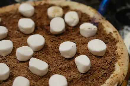 Pizza doce de chocolate com marshmallow sendo finalizada no maçarico