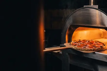 Pizzaiolo da BeatOven tirando pizza do forno em um evento