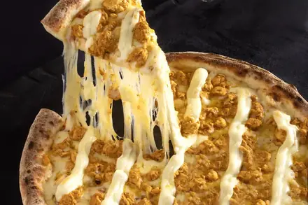 Pizza de frango com requeijão, do cardápio Repertório, puxando o queijo