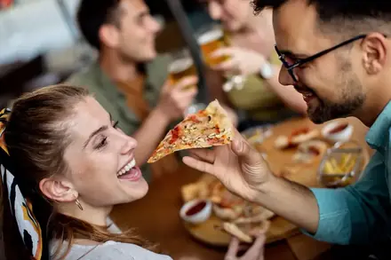 Amigos dividindo pizza à mesa durante uma festa