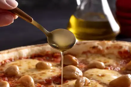 Pizza com cogumelos recebendo um fio de azeite, da BeatOven