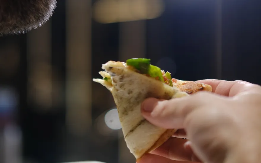 Convidado comendo uma fatia de pizza dobrada em um evento