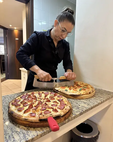 Garçonete da BeatOven cortando a pizza para servir