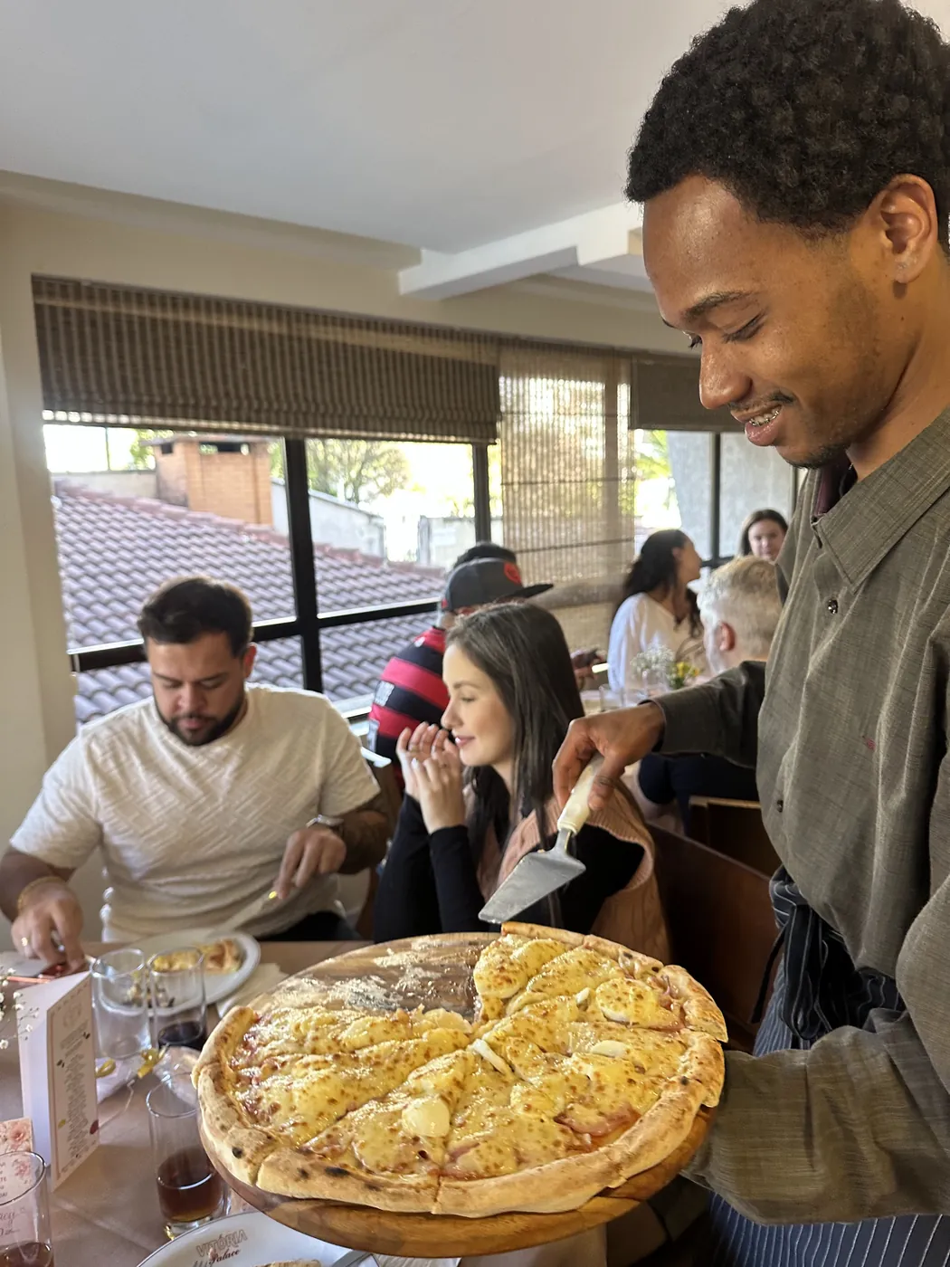 Garçom servindo pizza na mesa dos convidados