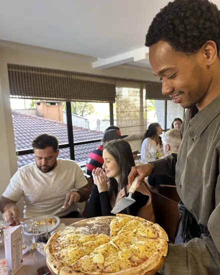 Garçom servindo pizza na mesa dos convidados
