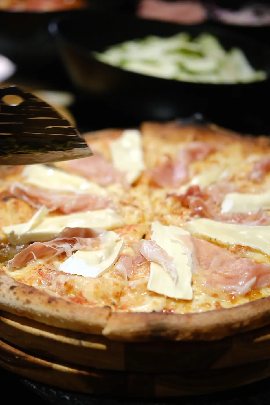 Pizza de presunto cru com queijo brie servida na tábua durante um evento