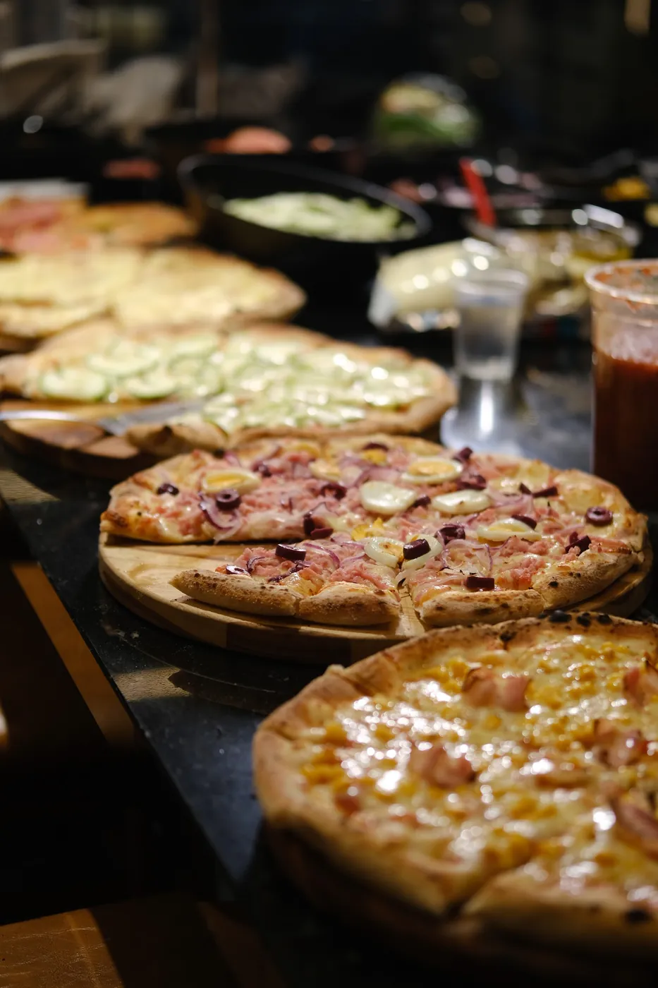Várias pizzas do rodízio na bancada montada no local do evento
