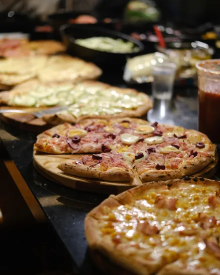 Várias pizzas do rodízio na bancada montada no local do evento