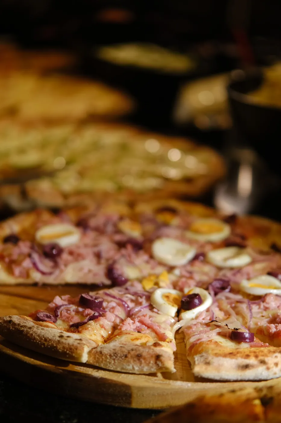Pizza portuguesa com presunto, ovo, cebola roxa e azeitona, servida na tábua durante um evento da BeatOven