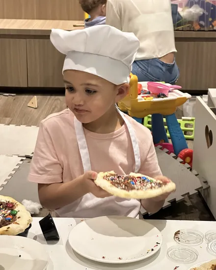 Criança mostrando a pizza doce que decorou no Mini Chef