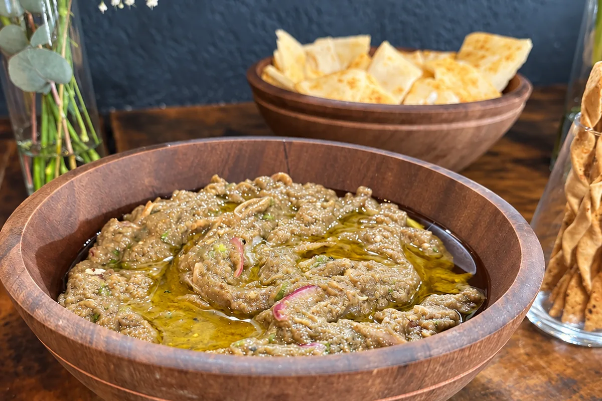 Antepastos servidos na mesa de frios, com baba ganoush e pães