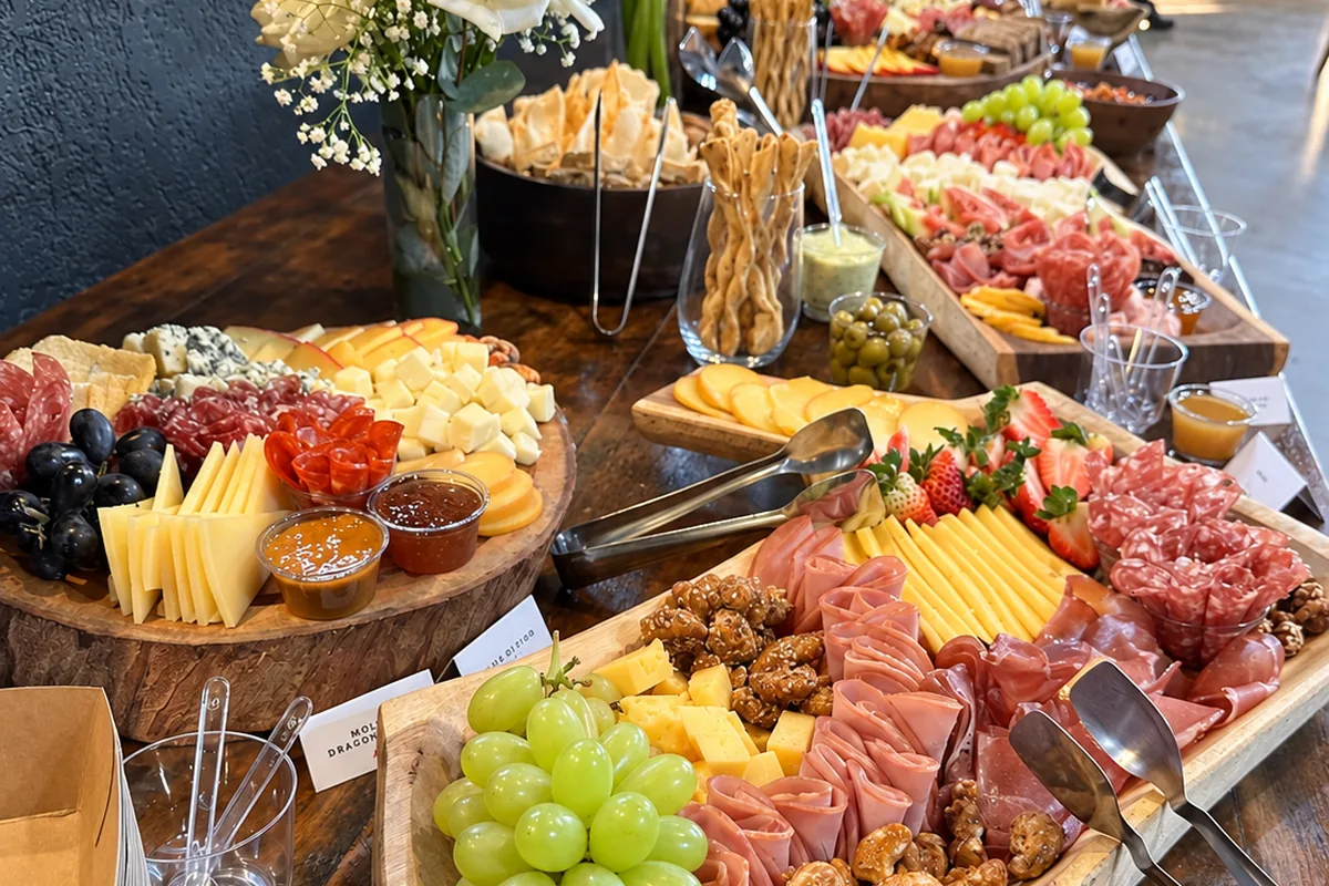 Mesa de frios da recepção, com flores e tábuas em fila