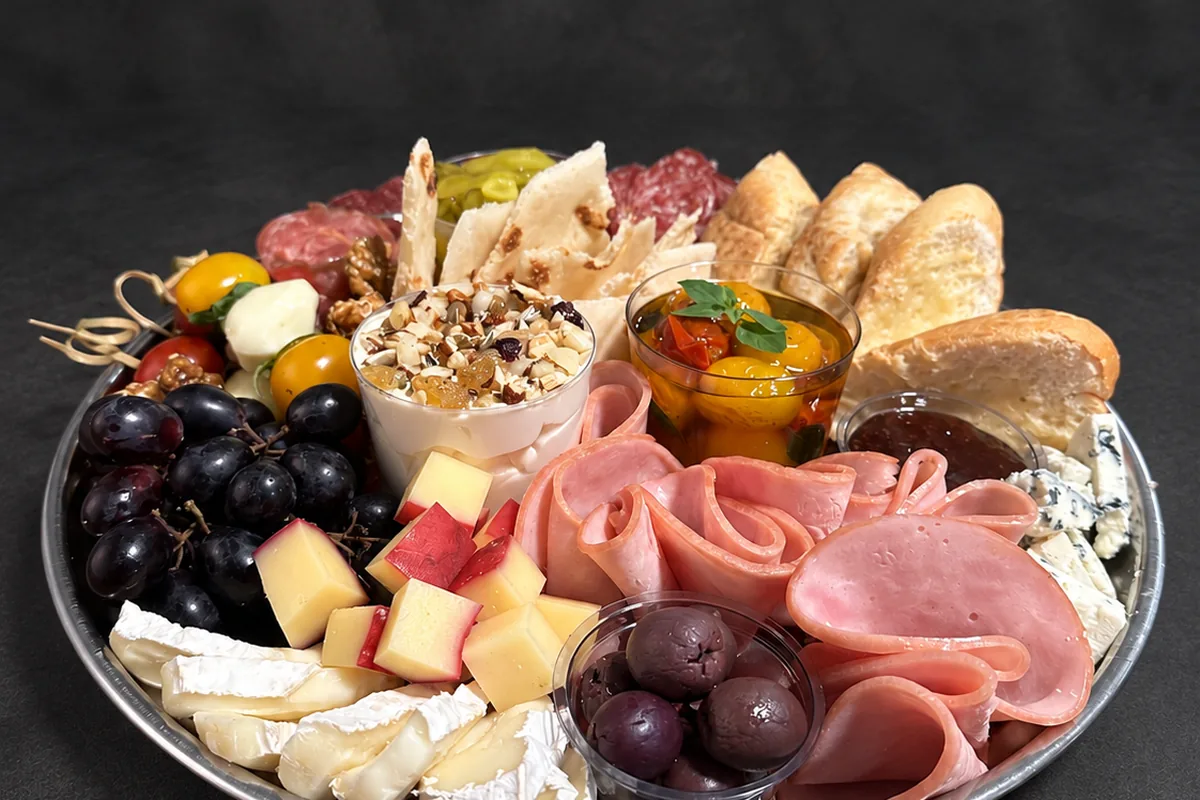 Bandeja prateada de frios com brie, uvas e azeitonas