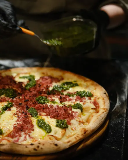 Pizza de calabresa com pesto na tábua