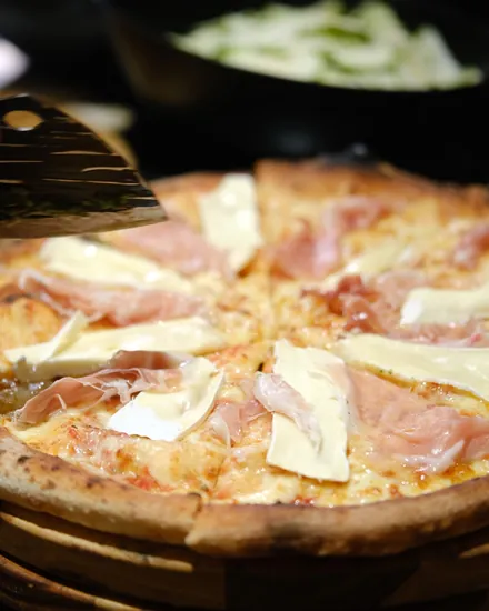 Pizza de presunto cru com queijo brie servida na tábua durante um evento