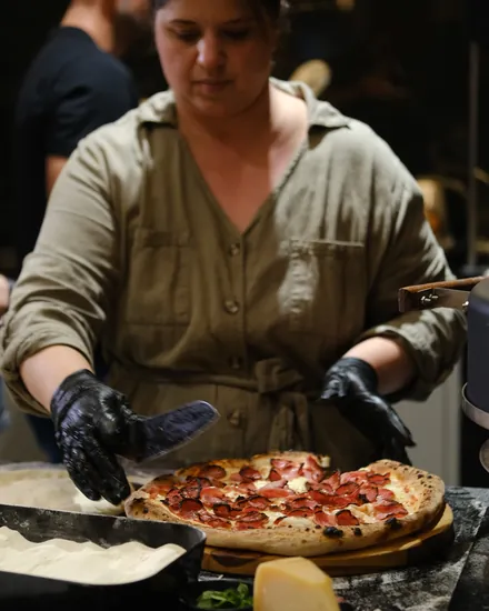 Pizzaiola da BeatOven montando uma pizza na bancada do evento