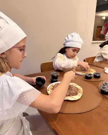 Criança de chapéu de cozinheiro decorando a pizza doce