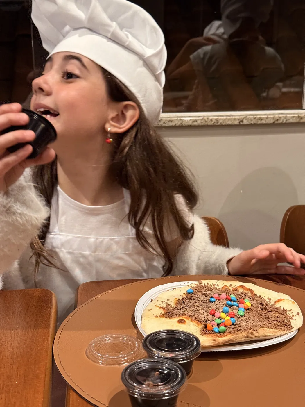 Criança provando a pizza que decorou no Mini Chef