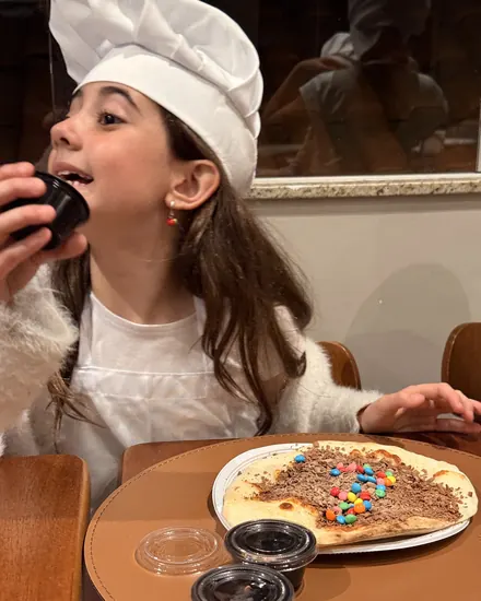 Criança provando a pizza que decorou no Mini Chef