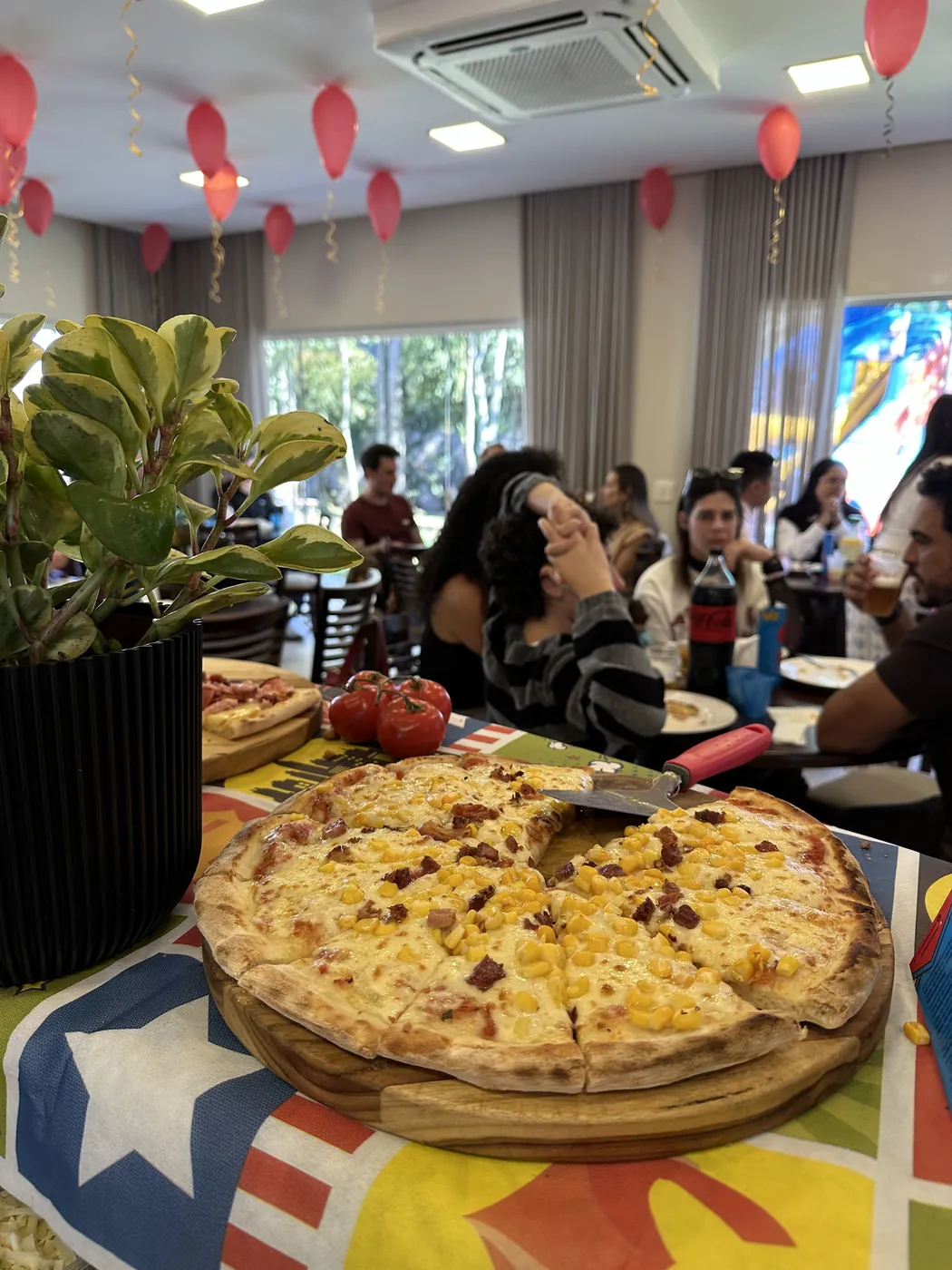 Salão da festa infantil com balões e as pizzas na mesa