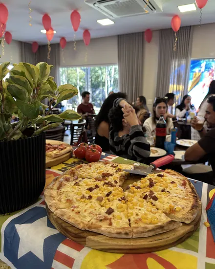 Salão da festa infantil com balões e as pizzas na mesa
