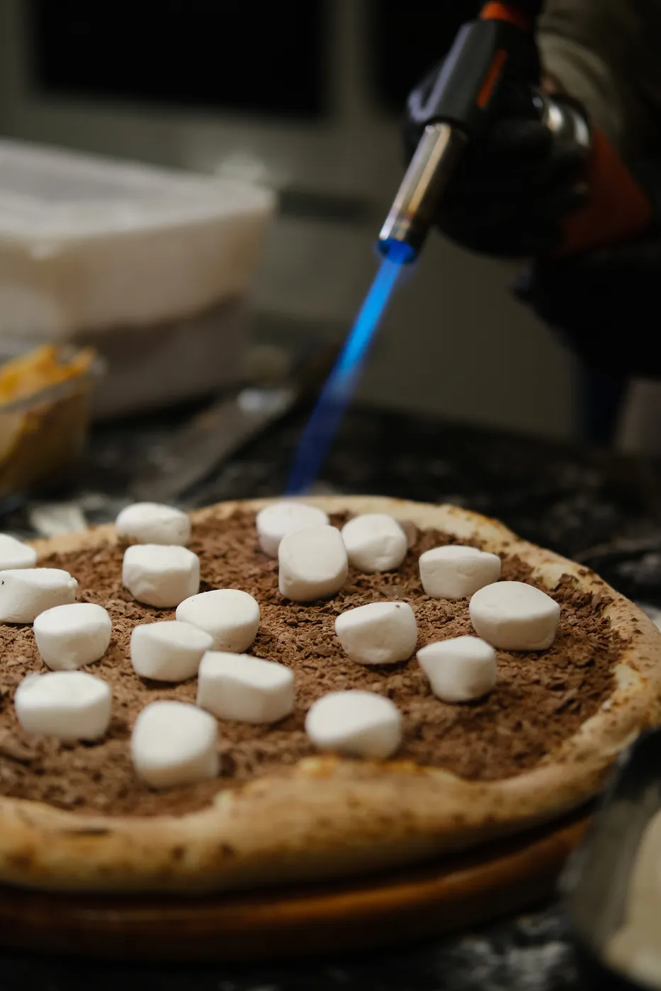 Pizza doce de chocolate com marshmallow sendo finalizada no maçarico