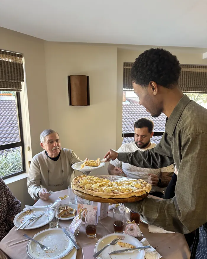 Garçom servindo pizza na mesa dos convidados