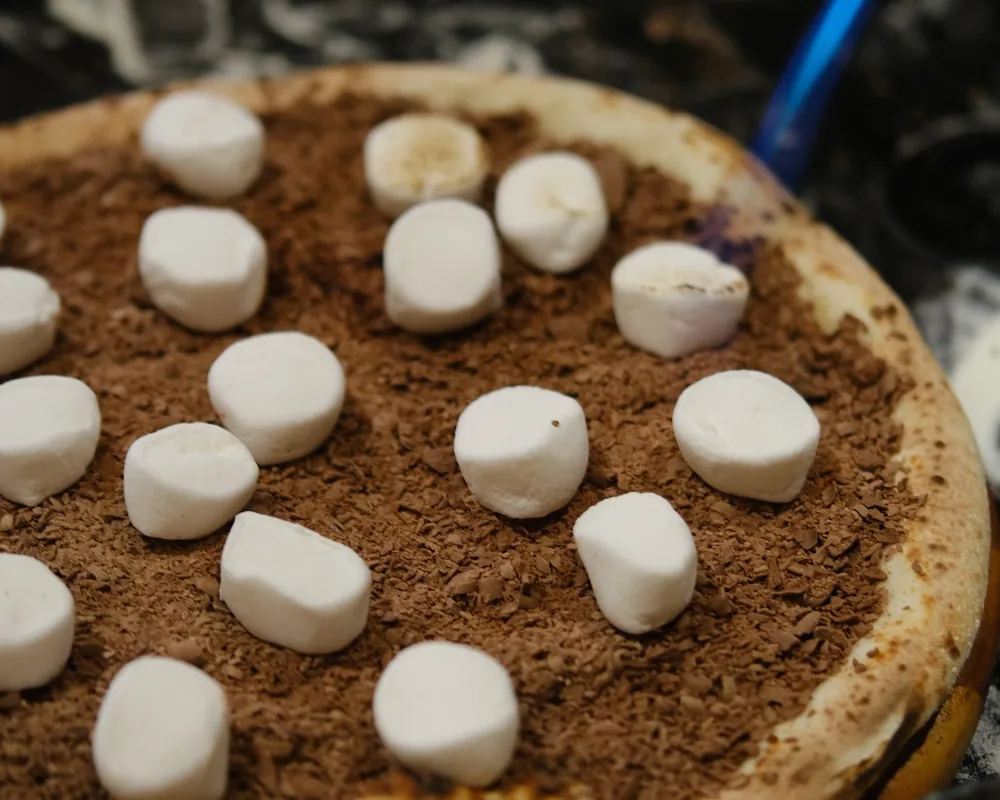 Pizza doce de chocolate com marshmallow sendo finalizada no maçarico